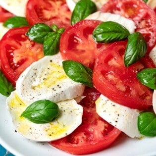 A caprese salad on a white platter.