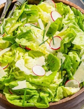 Butter lettuce salad in a serving bowl with serving utensils.