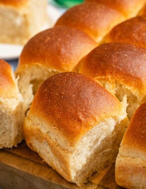 A close up of dinner rolls on a wooden cutting board.