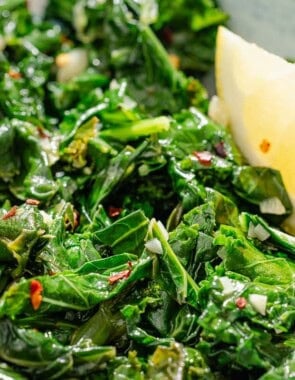 A close up of horta with a lemon wedge.