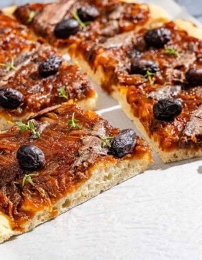 Sliced Pissaladière on parchment paper.