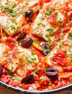 A close up of provençal fish in a cast iron skillet.