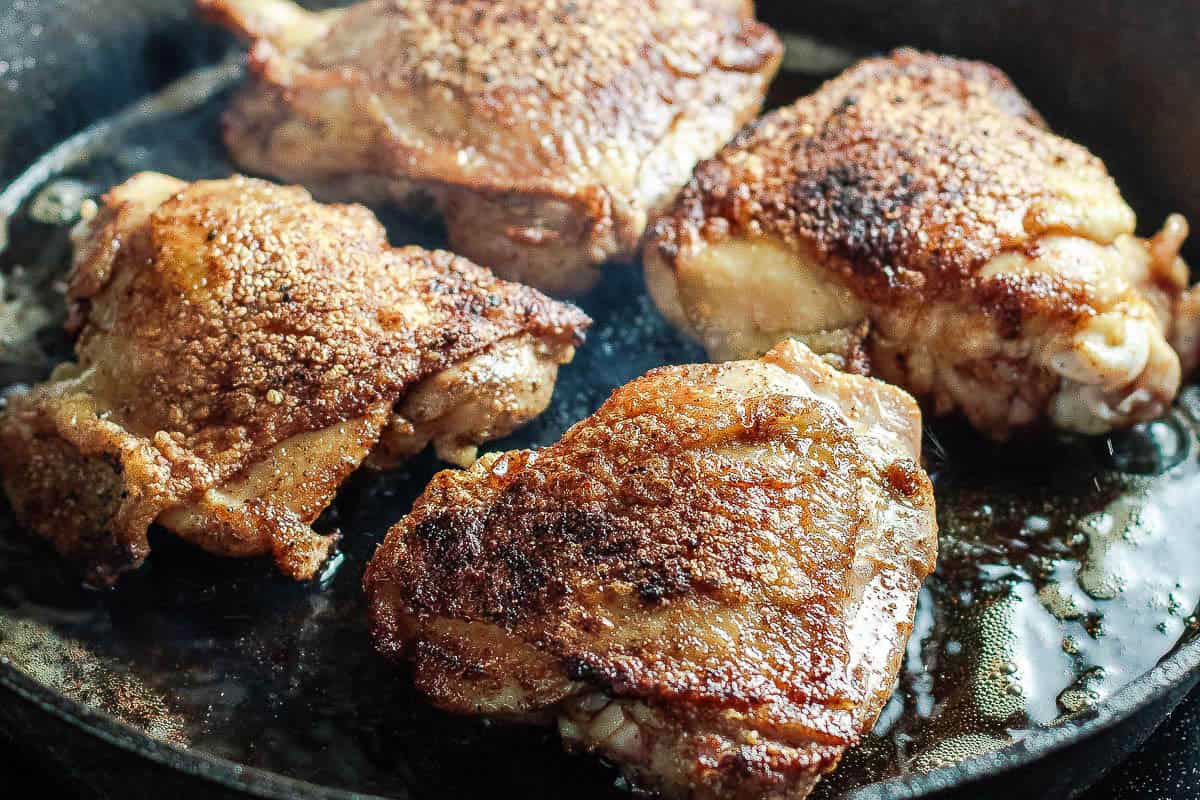 Side shot of seasoned chicken that has been rendered in a cast iron skillet for the cilantro lime chicken recipe, showing the golden brown and crispy skin.
