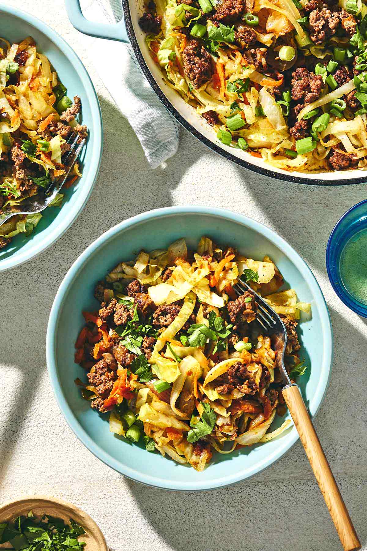 two bowls of beef and cabbage and a skillet of Mediterranean cabbage with ground beef