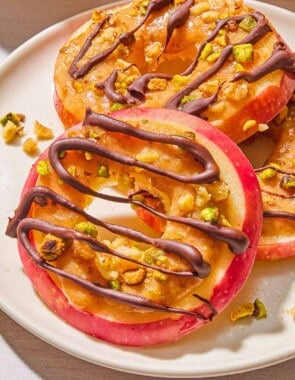 A close up of 3 caramel apple slices on a plate.