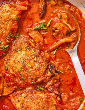 Chicken chasseur in a skillet with a serving spoon.