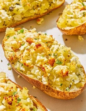 A close up of a twice baked potato surrounded by other twice baked potatoes.