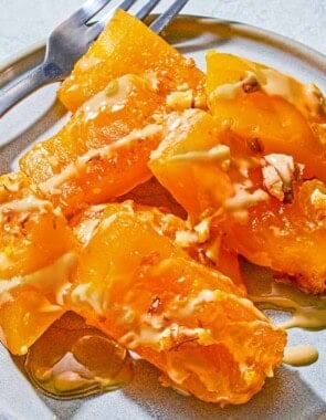 Kabak Tatlisi drizzled with tahini and topped with walnuts on a plate with a fork.