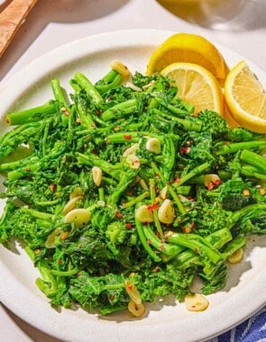 Broccoli rabe on a platter with lemon wedges.