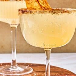 A close up of a ginger beer mocktail garnished with a candied pear chip on a wooden platter with another in the background.