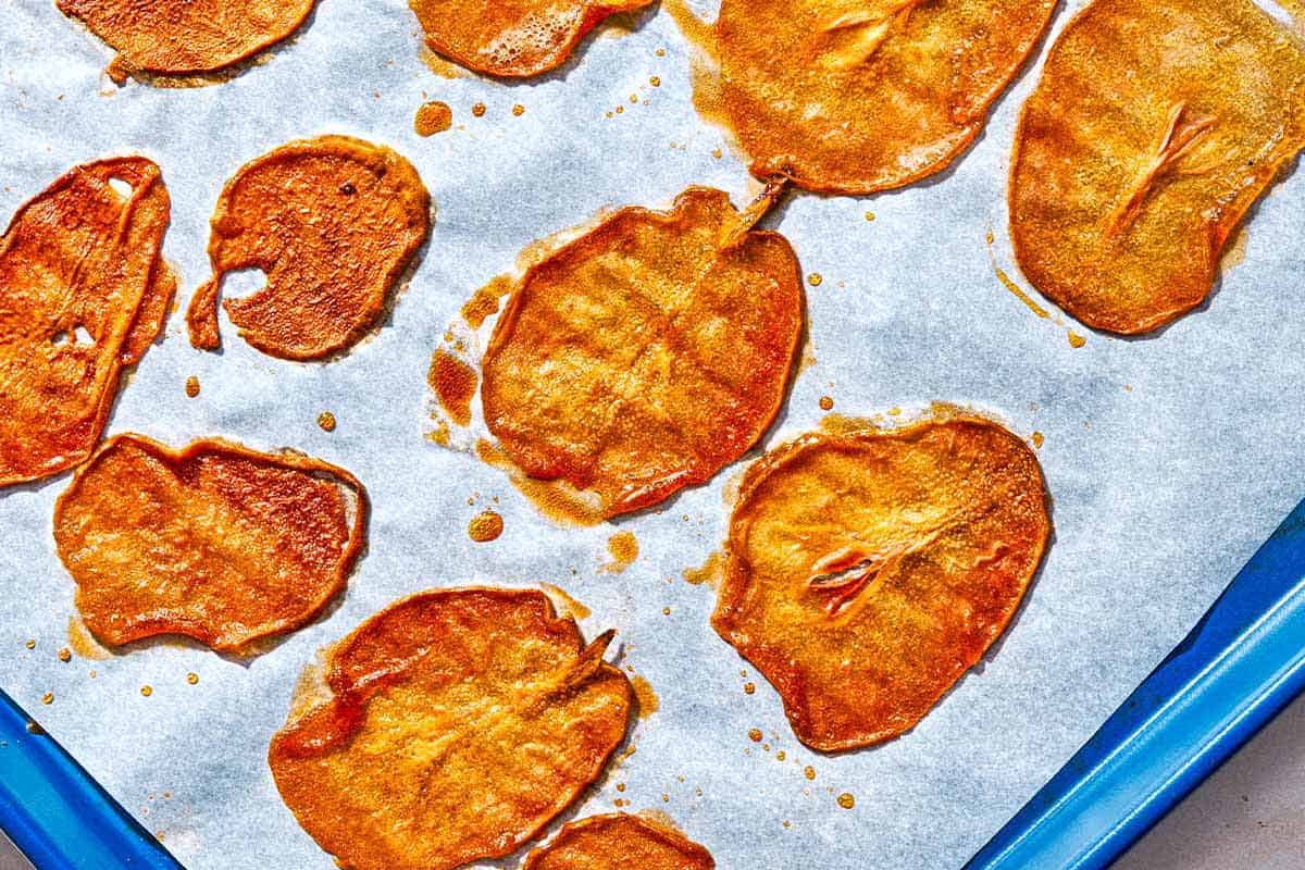 Baked pear chips on a parchment lined sheet pan.