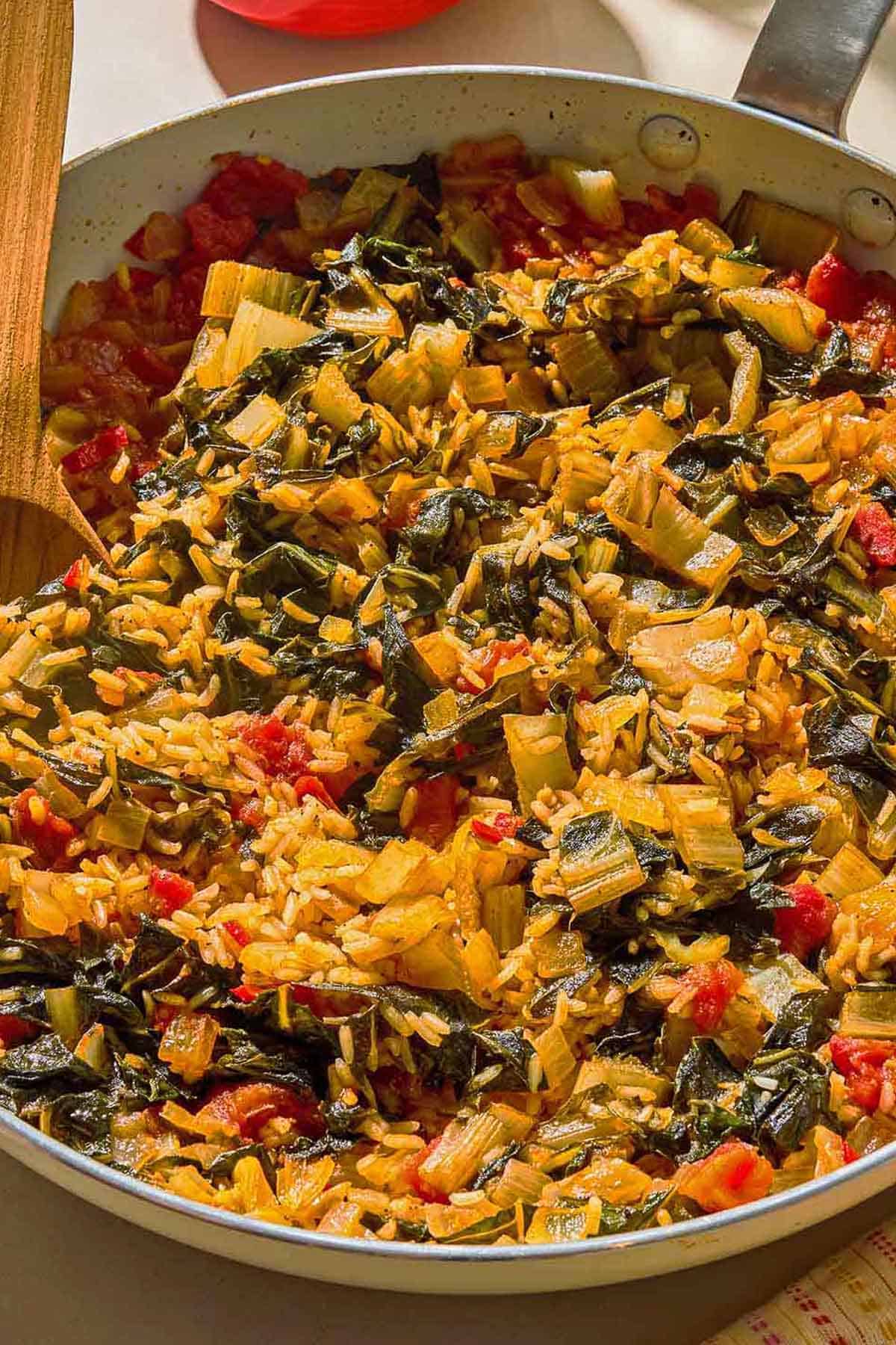 Swiss chard in a skillet with a wooden spoon.