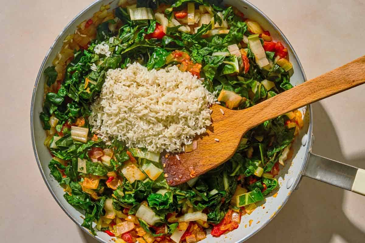 All of the ingredients for the swiss chard recipe in a skillet just before being mixed together with a wooden spoon.