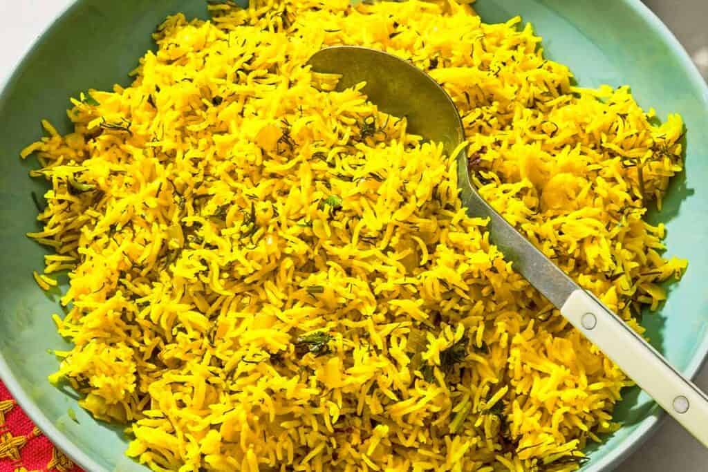 Turmeric rice in a serving bowl with a spoon.
